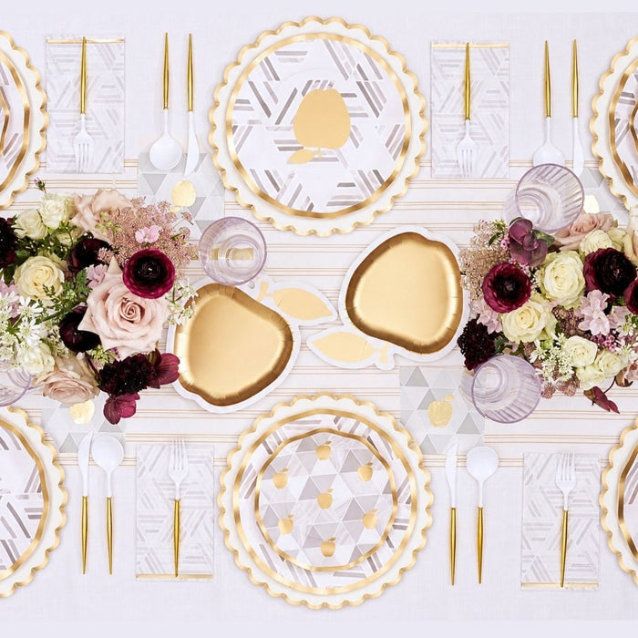 Golden Apple Table Setting by Sophistiplate: Elevate your Rosh Hashanah celebration with this elegant set, featuring gold and white designer disposable plates, gold utensils, clear glasses, pastel napkins, and stunning floral centerpieces in pink, white, and burgundy—all artfully arranged atop a geometric-patterned tablecloth.