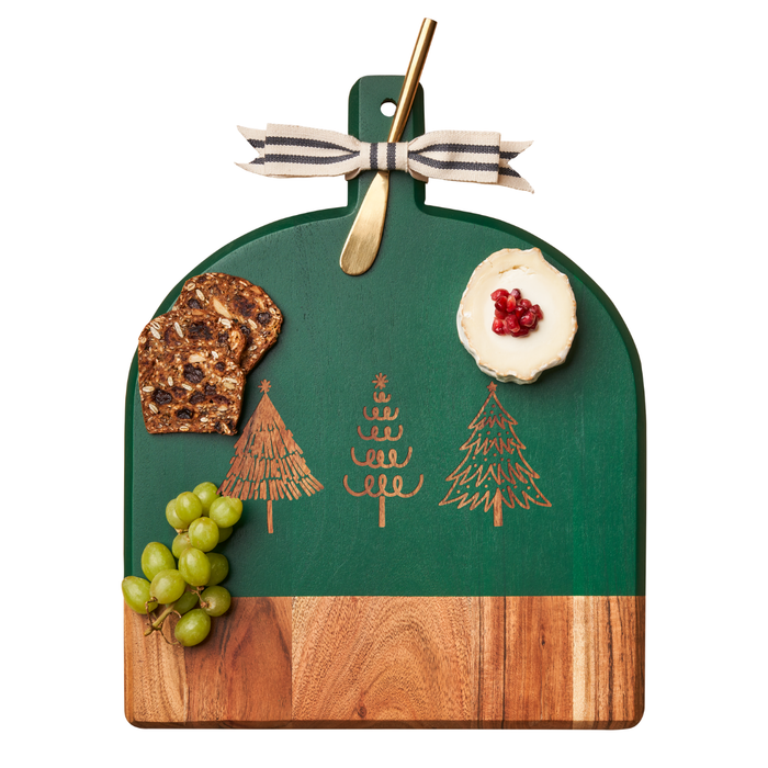 The Maple Green Acacia Bevel Board with Christmas tree designs (15 x 12") comes with a spreader and festive ribbon, beautifully displaying grapes, crackers, and a cheese cracker topped with pomegranate seeds.