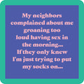 Drinks On Me's Groaning Coaster features a blue background, green border, and pink text: "My neighbors complained about me groaning too loud having sex in the morning... If they only knew I'm just trying to put my socks on..." Funny for drinks or housewarming gifts!.
