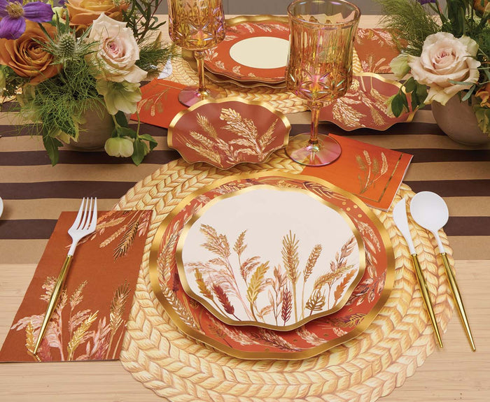 Elegant table setting featuring Sophistiplate Harvest Wheat Salad Plates (8pk) with gold cutlery, amber glasses, rust-colored napkins, and floral centerpieces on a woven placemat and brown-striped table runner.