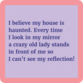 The Haunted Coaster by Drinks On Me features a lavender square with a pink border and the text: "I believe my house is haunted. Every time I look in my mirror, a crazy old lady stands in front of me so I can’t see my reflection!" Great for funny gifts.
