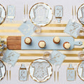 The Hey Baby Blue Table Setting by Sophistiplate LLC features designer disposable onesie-shaped plates in blue and gold, "Oh Boy!" napkins, gold utensils, cupcakes with frosting, and a gold-striped table runner for your baby shower.