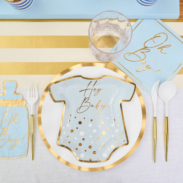 The Hey Baby Blue Table Setting by Sophistiplate LLC features a onesie-shaped plate with "Hey Baby!", gold-rimmed plate, blue "Oh Boy!" napkins, gold utensils, plastic cup, and gold-white striped placemat.