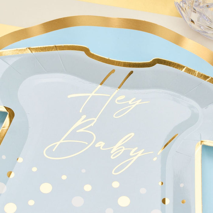 Close-up of Sophistiplate LLC’s Hey Baby Blue Table Setting: a pastel blue and gold designer plate shaped like a baby onesie with "Hey Baby!" in cursive and polka dots, displayed on a coordinating background.