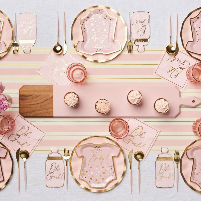 The Hey Baby Blush Table Setting by Sophistiplate LLC includes a striped table runner, onesie-shaped plates, "Oh Girl" napkins, pink cups, gold cutlery, cupcakes, and a wooden serving board for easy party styling.