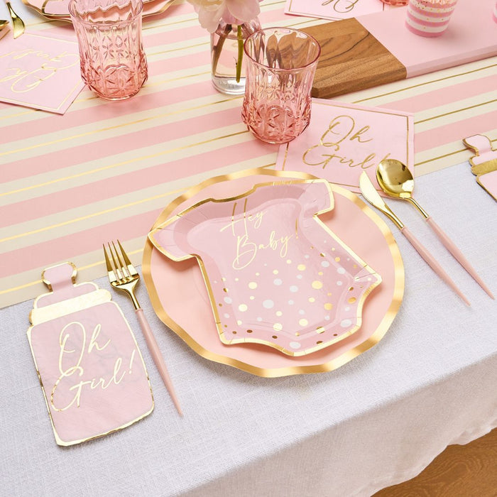 The Hey Baby Blush Table Setting by Sophistiplate LLC features pink and gold onesie-shaped plates, Oh Girl! napkins, baby bottle napkins, pink utensils, and glasses on a striped pink and yellow table runner.