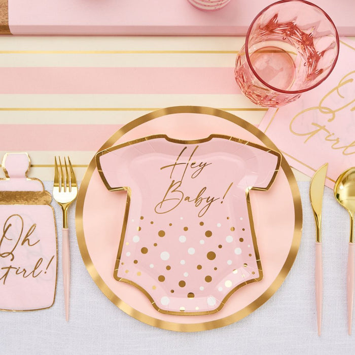The Hey Baby Blush Table Setting by Sophistiplate LLC includes onesie-shaped plates with “Hey Baby!”, pink “Oh Girl!” napkins, gold cutlery, and a pink glass on a striped placemat—a perfect party-in-a-box for your baby shower.
