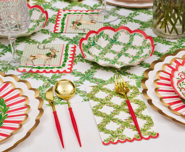 Create a festive holiday tablescape with the Holly Berry Table Setting by Sophistiplate, featuring red, white, and gold designer plates, gold utensils with red handles, green leaf napkins, and deer-themed tablecloth and coasters.