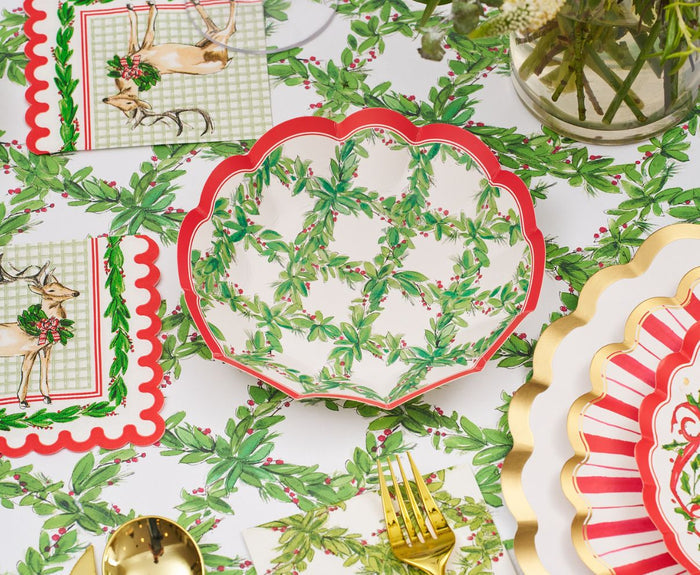 Create a festive holiday table with the Holly Berry Table Setting by Sophistiplate, featuring designer disposable plates, napkins, and a tablecloth adorned with holly patterns, gold and red accents, plus reindeer details for Christmas charm.