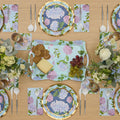 The Hydrangea Table Setting by Sophistiplate includes designer floral plates, matching napkins, a serving tray, and is arranged for four with cheese, crackers, grapes, white flowers in vases, forks, spoons, and clear glasses.