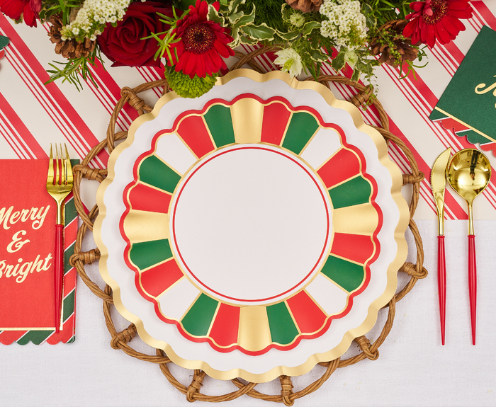 Create a festive holiday table with Sophistiplate Joyful Christmas Dinner Plates (8pk), gold utensils with red handles, a "Merry & Bright" napkin, and a red floral centerpiece on a striped runner.