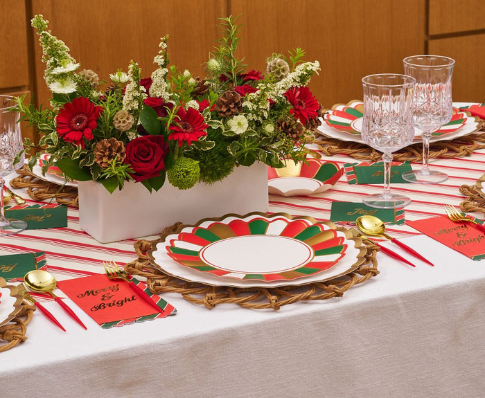 The Sophistiplate Joyful Christmas Table Setting includes vibrant disposable plates, crystal glasses, gold cutlery, and “Merry & Bright” napkins, plus a red and white floral centerpiece—everything you need for festive holiday table decor!.