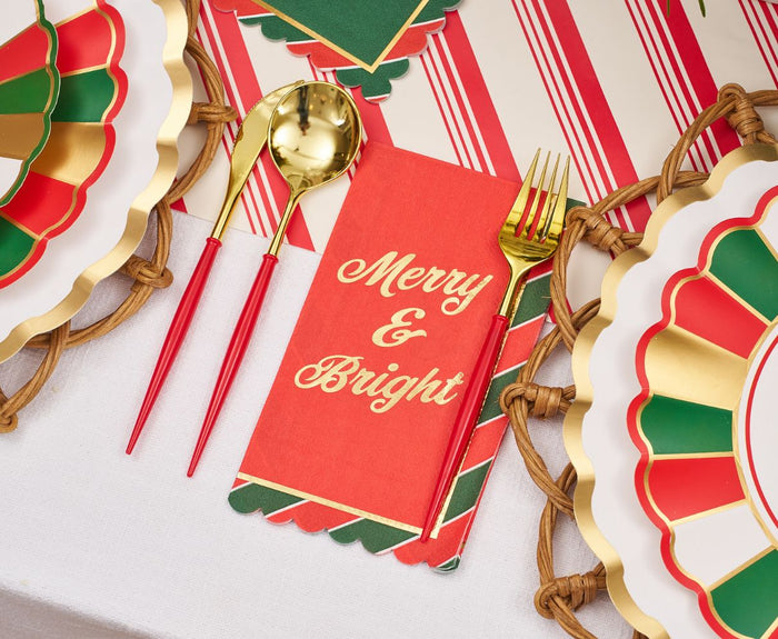 The Sophistiplate Joyful Christmas Table Setting includes gold utensils, a red "Merry & Bright" napkin, disposable plates in festive colors, woven placemats, and a candy cane-striped tablecloth—ideal for your holiday party.
