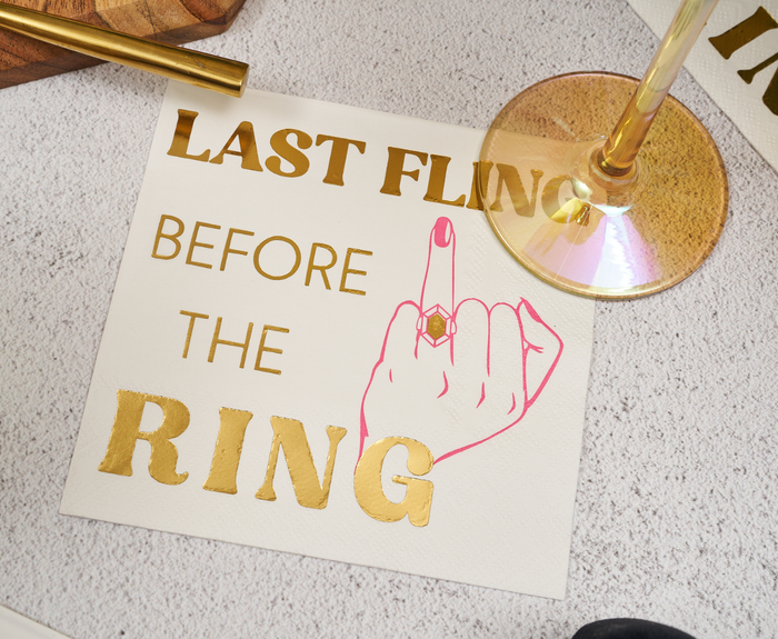 Sugarplum Last Fling before the Ring Cocktail Napkins (26pk) feature gold text and a ringed hand design—perfect bachelorette party napkins.