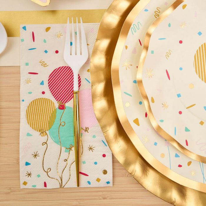The Sophistiplate Let's Celebrate Table Setting features festive plates and colorful balloon napkins with a gold fork, creating a vibrant tablescape-in-a-box on a light wooden table.