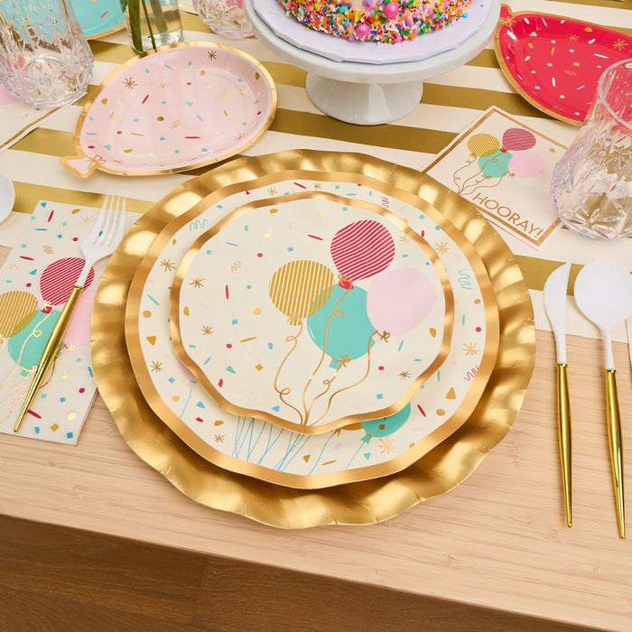 The Let's Celebrate Table Setting by Sophistiplate includes gold-rimmed designer plates, vibrant balloons, coordinated napkins and utensils. A sprinkle cake completes this festive scene for a bright, cheerful celebration.