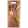 The Maple Live Edge Walnut Single Handle Charcuterie Board (24" x 12") displays a cheese wedge, soft cheese with red pepper slices, seed crackers, and green grapes arranged neatly on top.