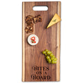 The Maple Live Edge Walnut Single Handle Charcuterie Board | Parisian Bites On Board (24" x 12") displays a cheese wedge, a small round cheese with pepper slice, crisps, and green grapes.