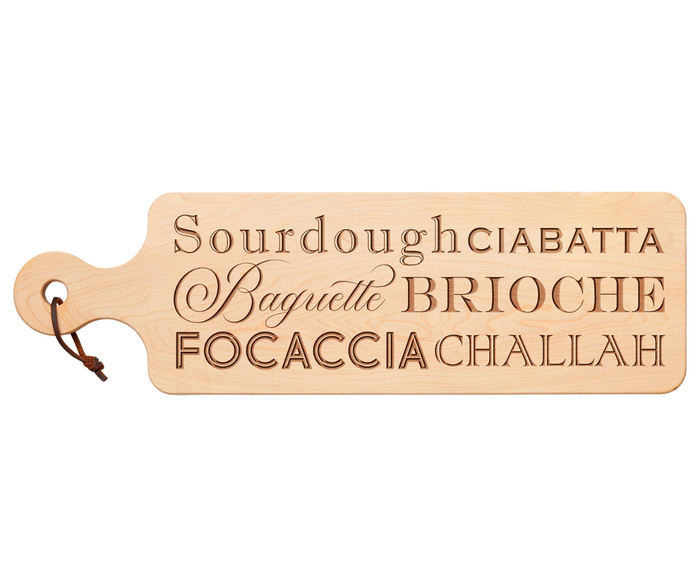 The Maple Wood Bread Board | Breads by Maple (20" x 6") features a handle, leather loop, and engraved bread names in stylish fonts—ideal as a cheese or charcuterie board for serving Sourdough, Ciabatta, Baguette, and more.