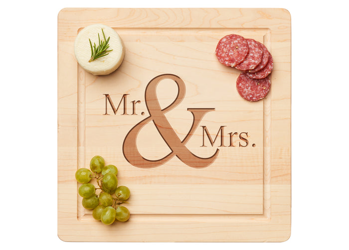 The Maple 12 x 12" Maple Wood Cutting & Cheeseboard Square, engraved with Mr & Mrs, beautifully displays rosemary cheese, salami slices, and green grapes for an elegant appetizer spread.