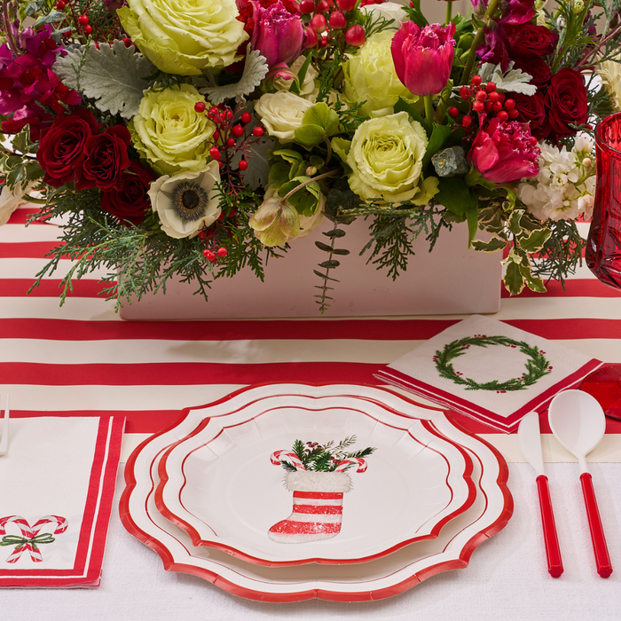 Cheerful Holiday Table Setup: Set a festive scene with Sophistiplate’s Merry and Bright Salad Plates (8-pack), featuring red and white stripes perfect for Christmas. Pair them with a napkin adorned with a candy cane, plastic cutlery, and a centerpiece of vibrant red, pink, and green flowers. A coordinating striped table runner completes the look, creating an inviting atmosphere for your holiday gathering.