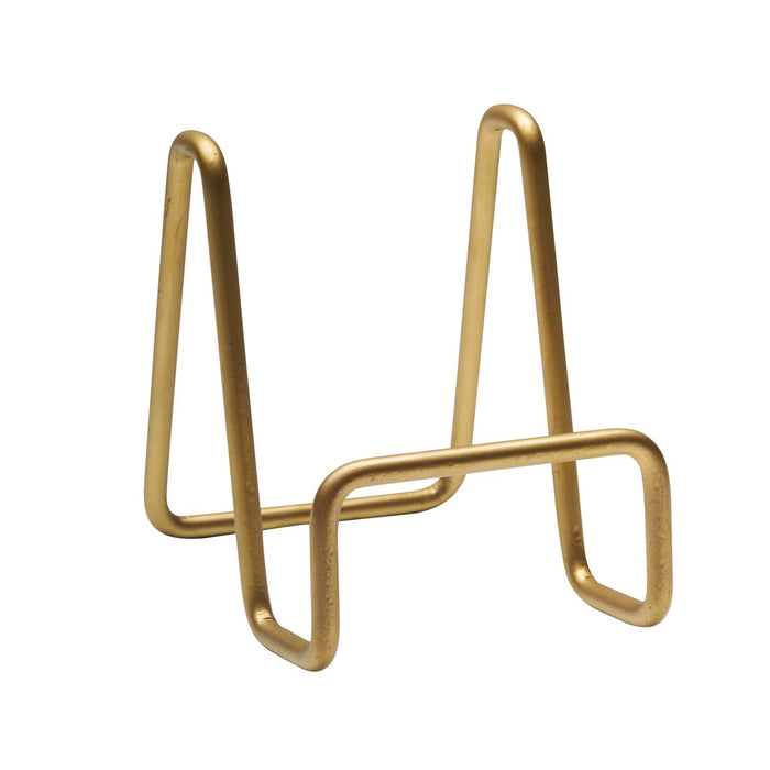 The Maple Metal Board Display Stand in matte gold features a minimalist geometric design with two angled supports and a horizontal base bar—an ideal, sleek holder for charcuterie boards on modern tabletops.
