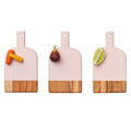 Three Maple Mini Bevel Boards - Set of 3 with Ribbon, Pink (8 x 4.25"), are arranged side by side with two carrot sticks on the left, a whole fig in the center, and a lime half on the right.
