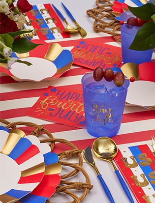 Celebrate the Fourth of July with a festive table featuring red, white, and blue plates, gold accents, blue cups with Stars in Stripes, Sophistiplate's Modern Patriotic Appetizer/Dessert Bowls (8pk), and "Happy Fourth of July" placemats.