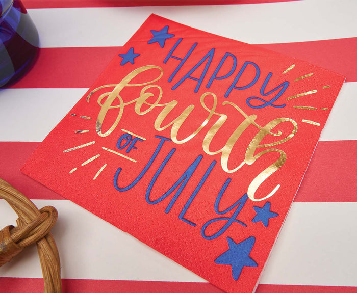 The Sophistiplate Modern Patriotic Cocktail Napkins Happy 4th/20pk feature red napkins with metallic gold and blue "Happy Fourth of July" lettering and blue stars, shown on a red and white striped surface.