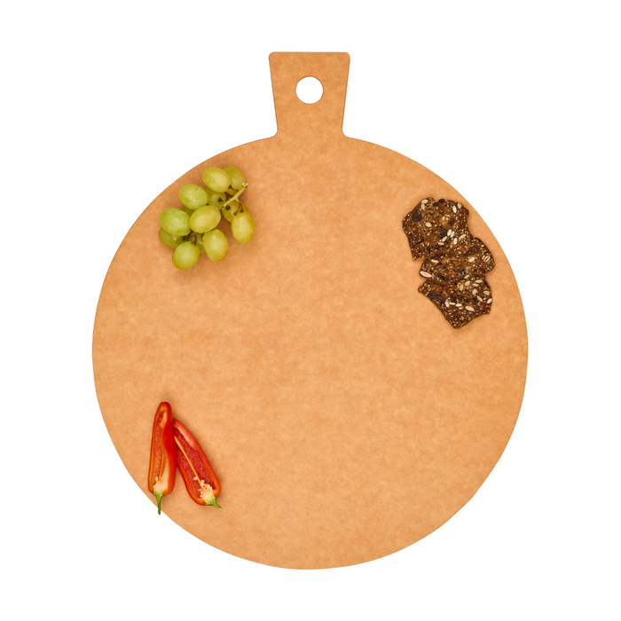 The Maple Natural Wood Composite Round Hostess Board, featuring a handle and hole, is shown on a white background with green grapes, crackers, and two red chili peppers arranged near the edges. This board is heat resistant.