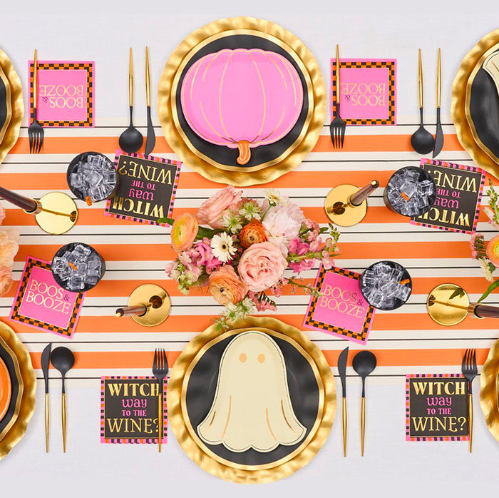 A festive Halloween table with a Hester & Cook Orange & Black Stripe Runner (20x25"), black and gold plates, pumpkin and ghost-shaped plates, floral centerpiece, gold cutlery, themed napkins, and black cups.