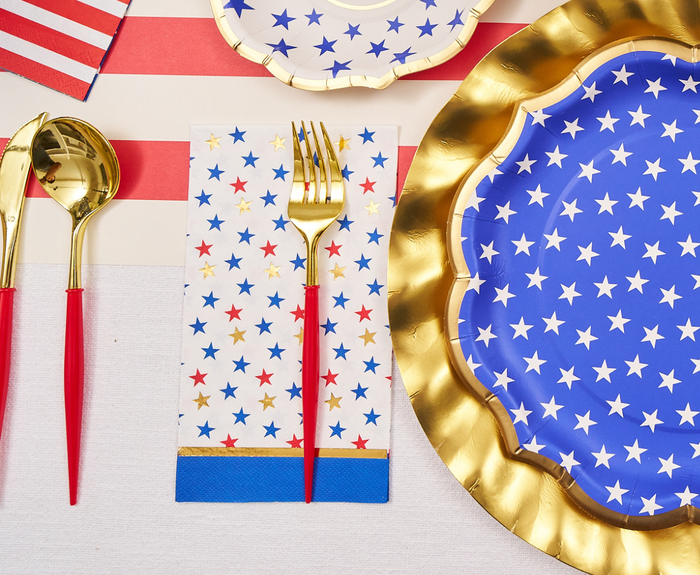 Create a festive July 4th table with Sophistiplate's Party in the USA Guest Towels (20pk), featuring colorful stars—perfect with gold utensils, blue and gold-edged plates for a vibrant patriotic celebration.