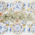 The Sophistiplate LLC Passover Tablescape for 16: Timeless features blue and white floral designer paper plates, gold-edged chargers, gold flatware, blue-handled knives, and a baby's breath centerpiece for an elegant and refined look.