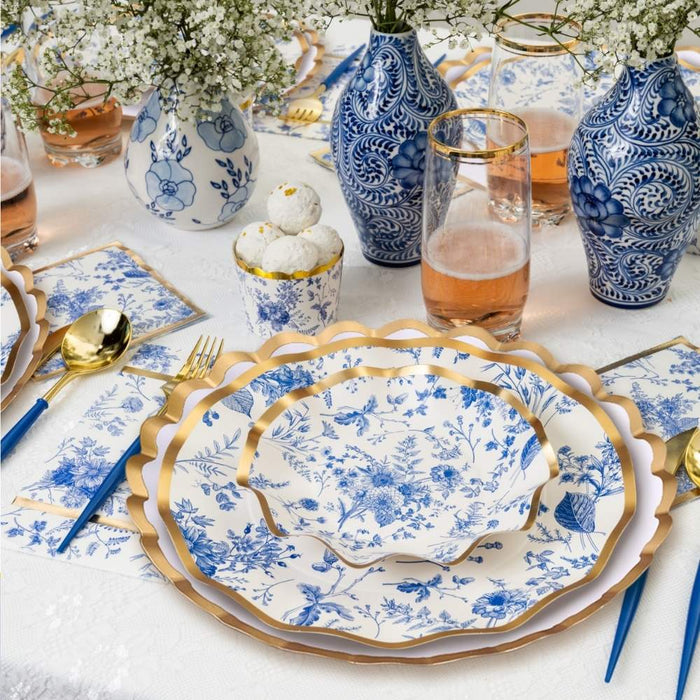 Create a stunning Passover table with Sophistiplate LLC's Passover Tablescape for 16: Timeless—designer blue-and-white floral plates with gold rims, gold cutlery, blue napkins, elegant drinkware, and floral centerpieces on a crisp white tablecloth.