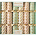 A box of twelve Peppermint Stripe Crackers by Hester & Cook in pastel pink, gold, and teal with diagonal gold stripes and gold ribbons; includes a choking hazard warning on the label.