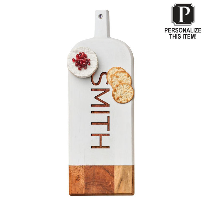 A Personalized Acacia Bevel Board by Maple in white (20" x 7" x .6") engraved with "SMITH," topped with a round cheese garnished with pomegranate seeds and two crackers. A "Personalize This Item!" label appears at the top right.