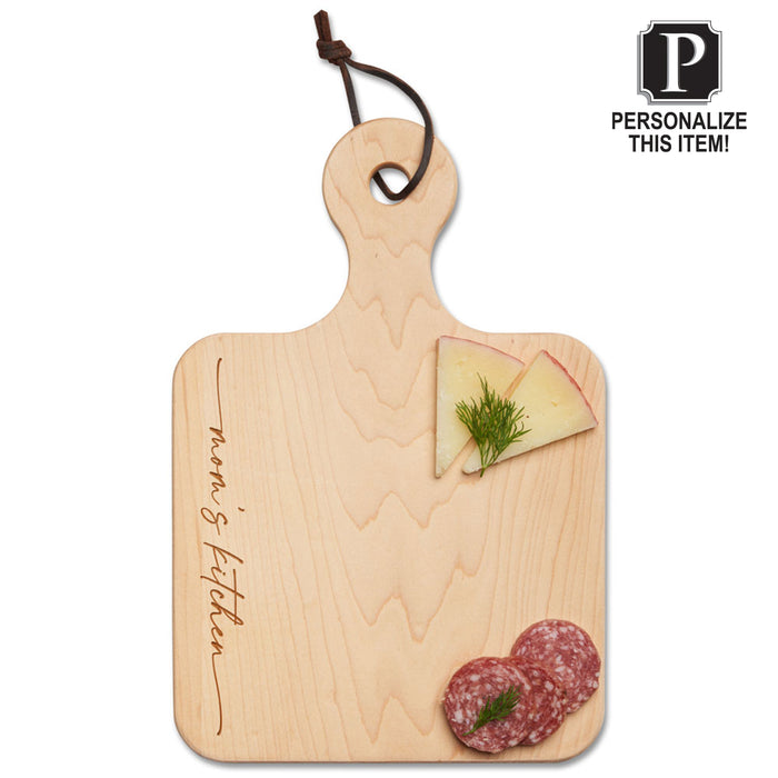 A 12 x 8" Maple Personalized Artisan Maple Paddle Board, engraved with "Mom's Kitchen," holds cheese slices with dill and salami. A "Personalize This Item!" label is at the top right. Brand: Maple.
