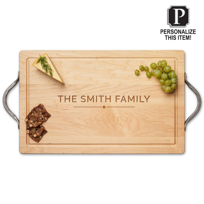 The Maple Personalized Maple Wood Cutting + Cheeseboard 18 x 12" features metal handles and engraving of THE SMITH FAMILY in the center, with cheese, grapes, and crackers displayed. A "Personalize This Item!" label appears in the top right corner.