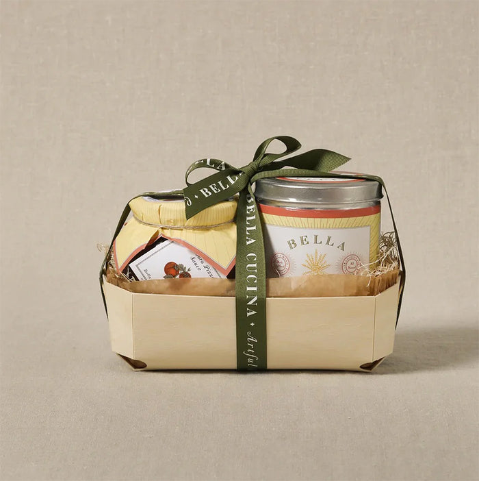 The Maple Personalized Pizza Peel Gift Set features two jars—one with a yellow lid, one with a silver lid—tied with a green Bella Cucina ribbon, displayed on a beige background.