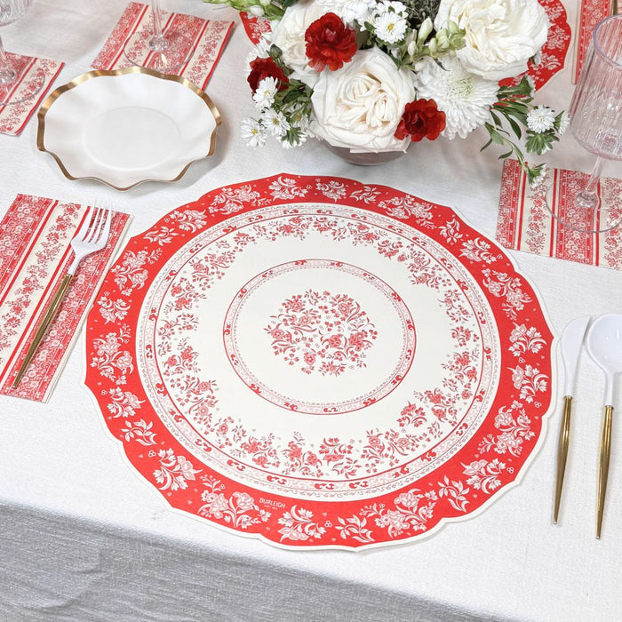 The Red Burleigh Table Setting by Sophistiplate includes a red and white floral plate, matching napkin, gold-handled cutlery, a white plate with gold rim, and a red and white floral centerpiece—all in one elegant box.