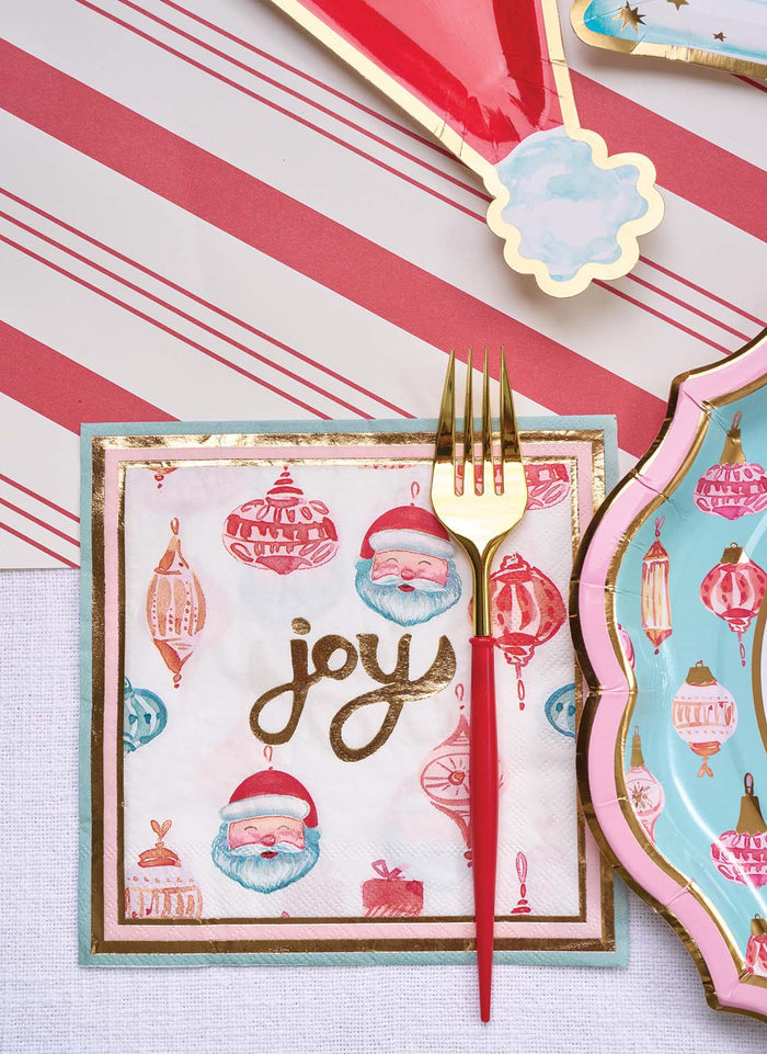 Create a festive table with Sophistiplate’s Red & Gold Bella Plastic Cutlery, a 24-piece BPA-free, reusable set for 8. Gold and red forks complement patterned plates atop a red-and-white striped tablecloth and Santa napkin with "joy.