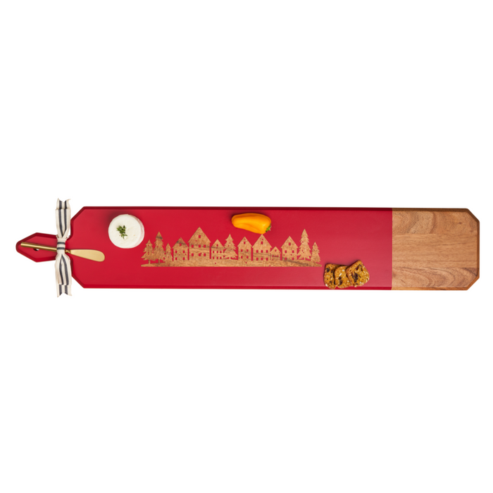 The Maple Acacia Heirloom Board Skinny in Red with gold spreader and Christmas Village design (34 x 6") elegantly serves creamy dip, yellow tomato, and grilled bread for a festive presentation.