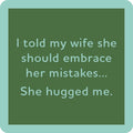 The She Hugged Me Coaster by Drinks On Me is a green square coaster with light blue text: "I told my wife she should embrace her mistakes... She hugged me." Great housewarming gift or quirky bar cart accessory.