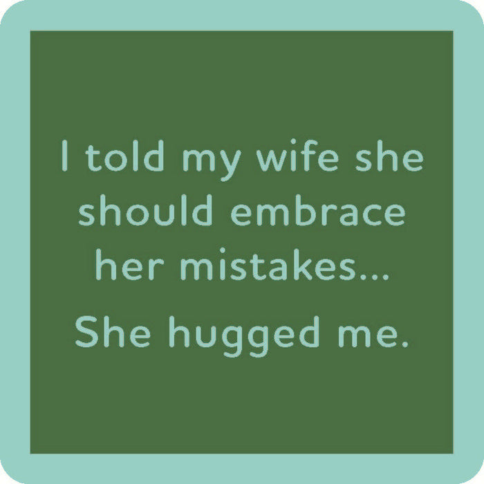 The She Hugged Me Coaster by Drinks On Me is a green square coaster with light blue text: "I told my wife she should embrace her mistakes... She hugged me." Great housewarming gift or quirky bar cart accessory.