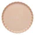An unfilled, uncooked round beige tart crust with fluted edges sits atop a Sophistiplate Simply Eco Salad Plate- Sand/8pkg, shown from above against a white background—an eco-friendly tableware option for sustainable baking.