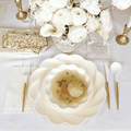 The Stunning Seder Table Setting by Sophistiplate includes designer disposable plates, gold cutlery, matzo ball soup, stacked decorative plates, matzo crackers, and a vase of white flowers on a crisp white tablecloth.