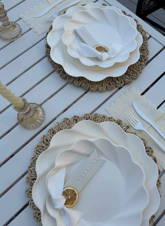 The Sophistiplate Stunning Seder Table Setting includes designer disposable plates, woven placemats, cream napkins, vintage-style glassware, candles, name tags, and dried lemon slices for each place setting.