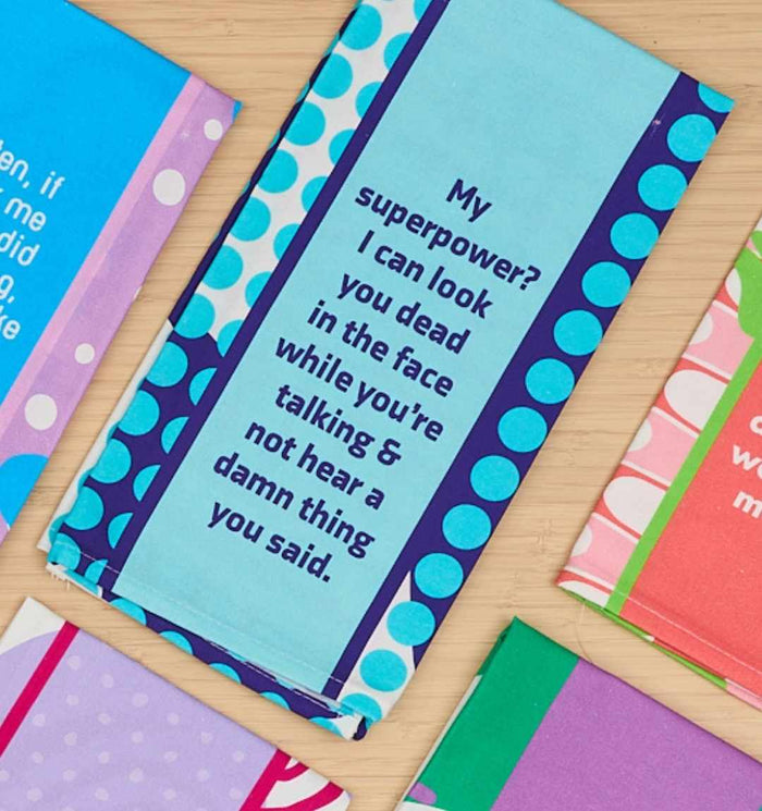 The "Superpower Dish Towel" by Drinks On Me features blue polka dots and the text: My superpower? I can look you dead in the face while you're talking & not hear a damn thing you said. A hilarious hostess gift—find more funny towels and patterned napkins nearby.