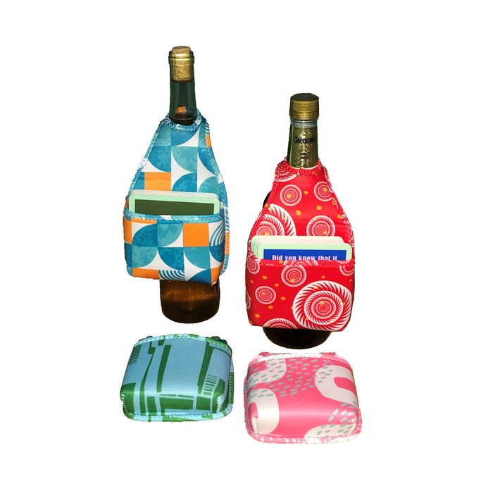 Two HOOK-r wine bottle accessories by Drinks On Me, each with a vibrant geometric or abstract pattern and card pocket, are shown on bottles with matching neoprene pouches—bright designs stand out on a white background.