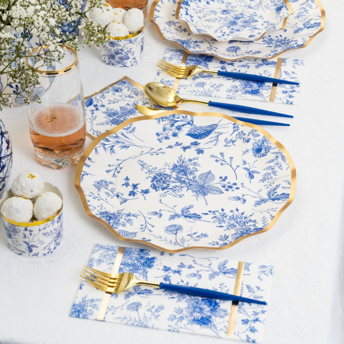 Create a chic Passover table with the Timeless Tablescape for 16 by Sophistiplate LLC—featuring designer white and blue plates with gold edges, coordinated blue and gold cutlery, glassware, floral accents, and treat cups.